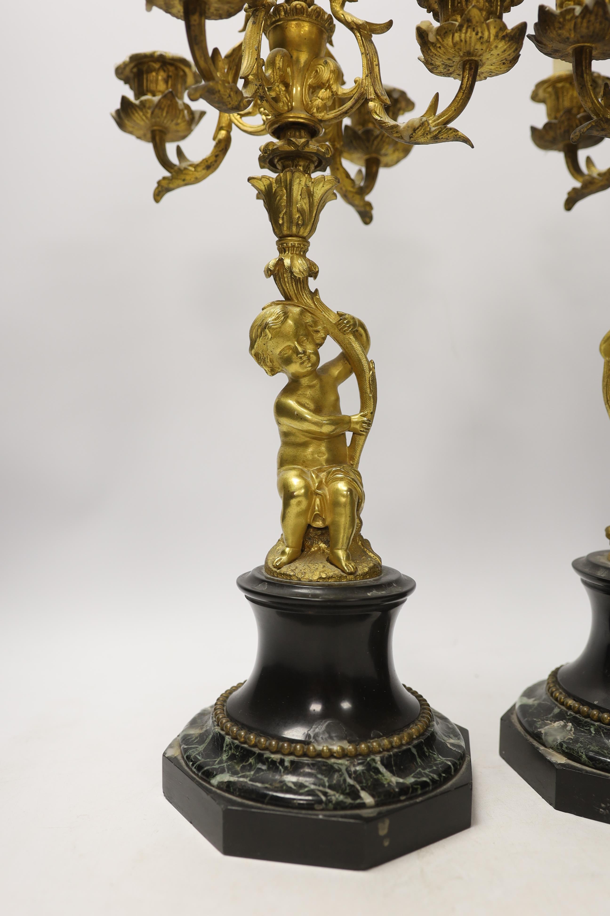 A pair of late 19th century French ormolu cherubic four branch candelabra on marble bases, 47cm